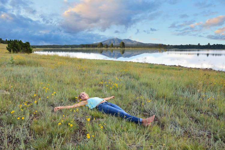 woman lying in the grass near a lake